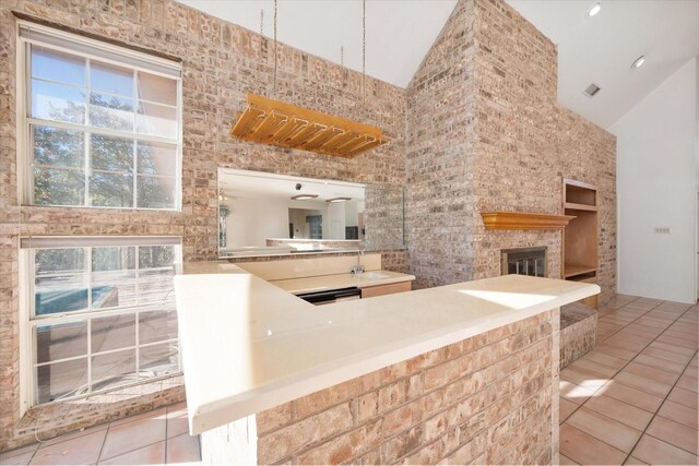 kitchen with kitchen peninsula, ceiling fan, high vaulted ceiling, and light tile patterned floors