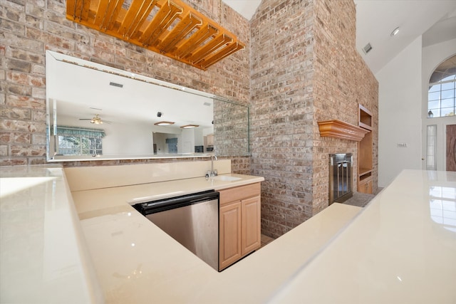 kitchen with ceiling fan, sink, light brown cabinets, a high ceiling, and brick wall