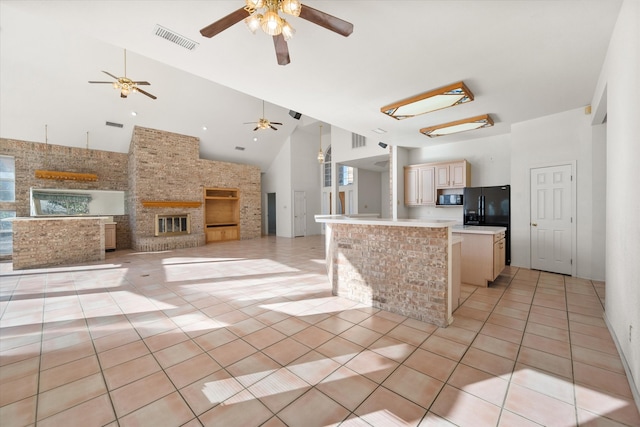 kitchen featuring a center island, high vaulted ceiling, black fridge, light tile patterned floors, and a fireplace