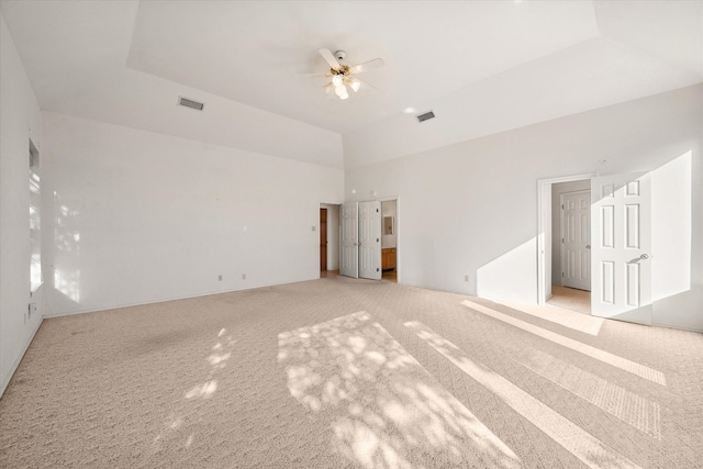 spare room featuring light carpet, a tray ceiling, and ceiling fan