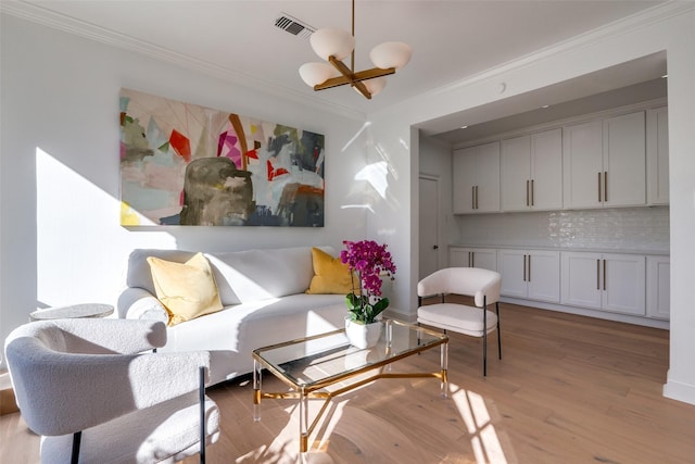 living area with light hardwood / wood-style floors, an inviting chandelier, and crown molding