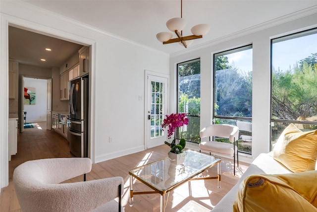 living room featuring wood-type flooring, ornamental molding, and an inviting chandelier