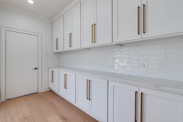 interior space featuring wood-type flooring, backsplash, and ornamental molding