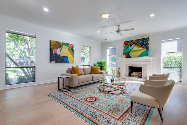 living room with ceiling fan, ornamental molding, and light wood-type flooring