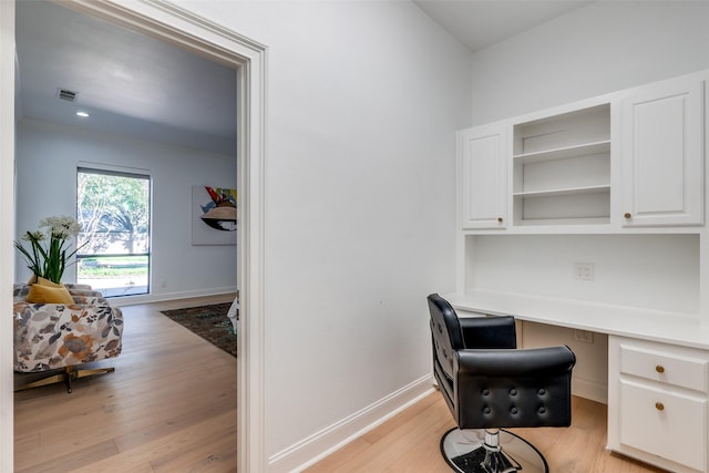 office with built in desk and light hardwood / wood-style flooring