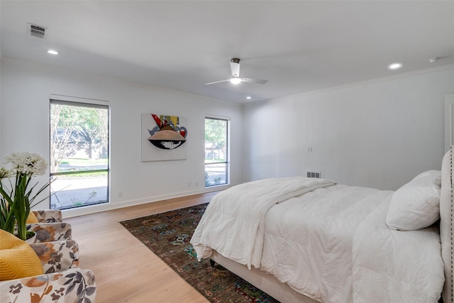 bedroom featuring hardwood / wood-style flooring, ceiling fan, crown molding, and multiple windows