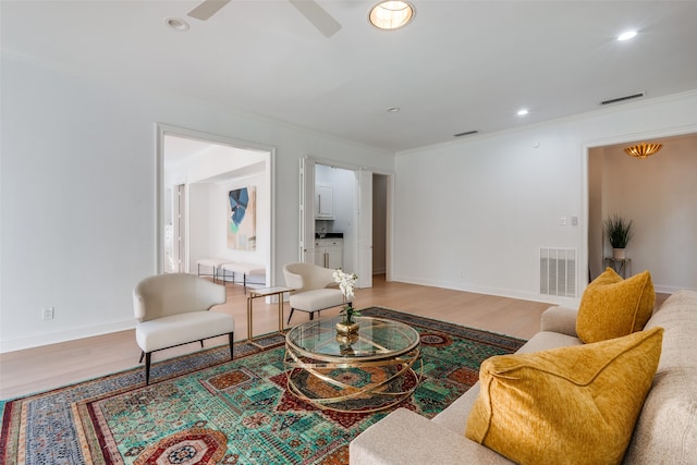 living room featuring hardwood / wood-style floors, ceiling fan, and crown molding