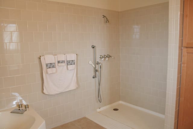 bathroom with tile walls, tile patterned flooring, and tiled shower