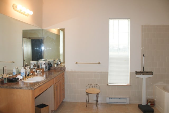 bathroom with vanity, a bathing tub, a baseboard heating unit, tile patterned floors, and tile walls