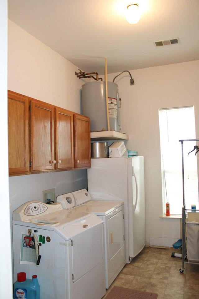 laundry area with plenty of natural light, water heater, cabinets, and washer and clothes dryer