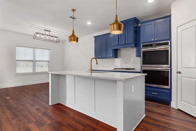 kitchen with an island with sink, appliances with stainless steel finishes, sink, and blue cabinetry