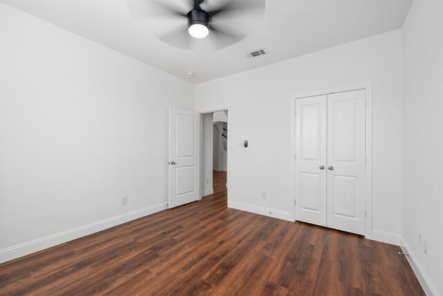 unfurnished bedroom featuring ceiling fan, dark hardwood / wood-style floors, and a closet