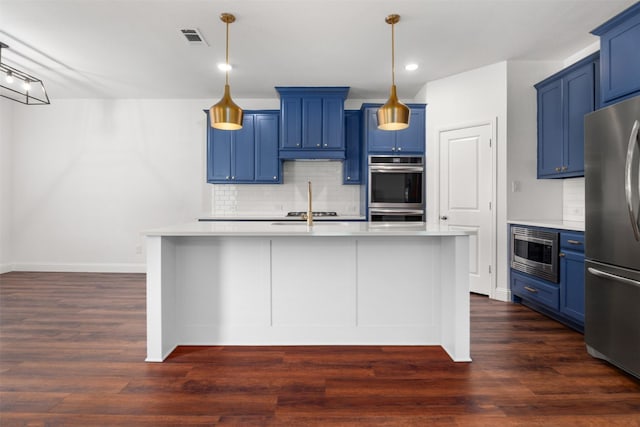 kitchen with appliances with stainless steel finishes, dark hardwood / wood-style floors, decorative light fixtures, a kitchen island with sink, and blue cabinetry