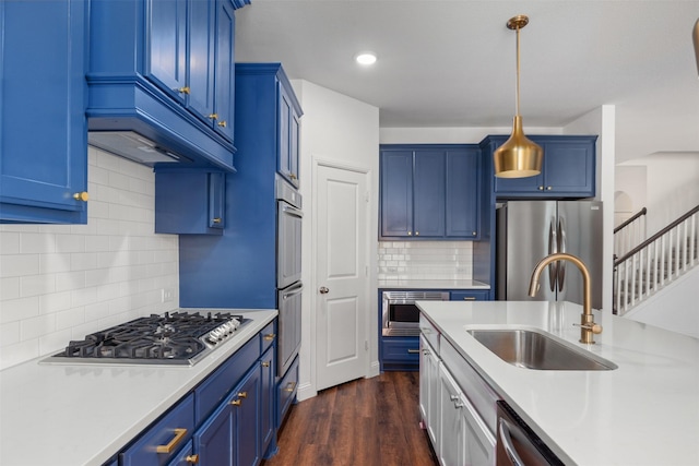 kitchen with sink, hanging light fixtures, stainless steel appliances, and blue cabinets