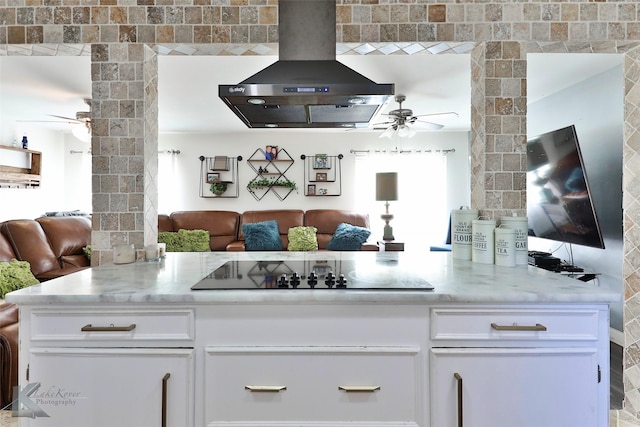 kitchen with white cabinets, black electric stovetop, light stone countertops, and wall chimney range hood