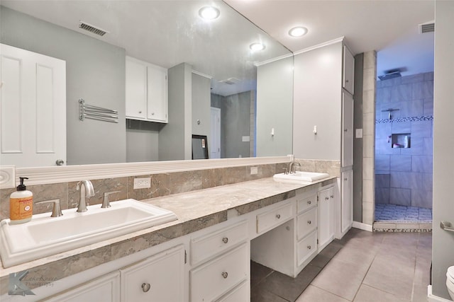 bathroom with tile patterned flooring, vanity, and tiled shower