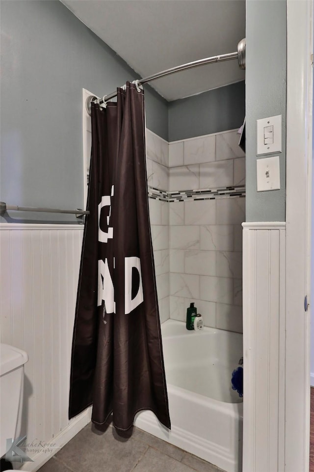 bathroom with tile patterned floors, shower / bath combination with curtain, and toilet