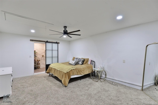 carpeted bedroom with a barn door and ceiling fan