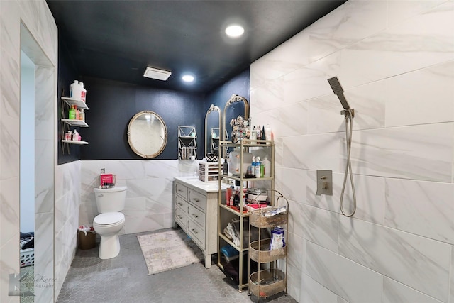 bathroom featuring vanity, toilet, tile walls, walk in shower, and concrete flooring