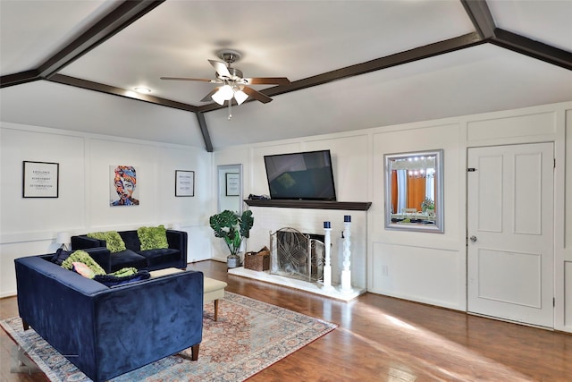 living room featuring lofted ceiling with beams, ceiling fan, wood-type flooring, and a fireplace