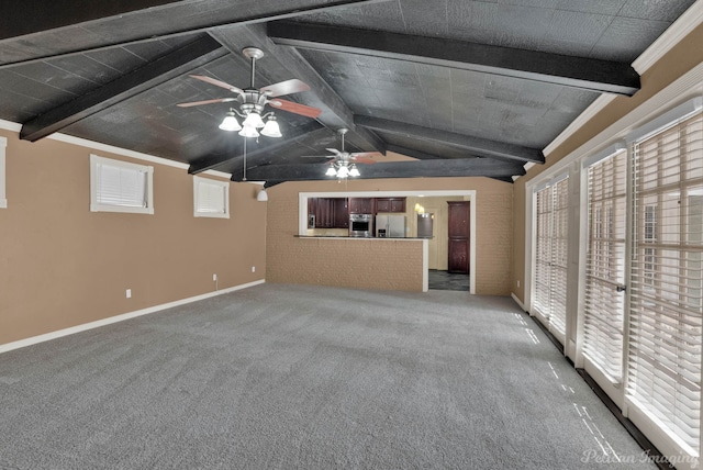 unfurnished living room featuring a wealth of natural light, lofted ceiling with beams, ceiling fan, and carpet flooring