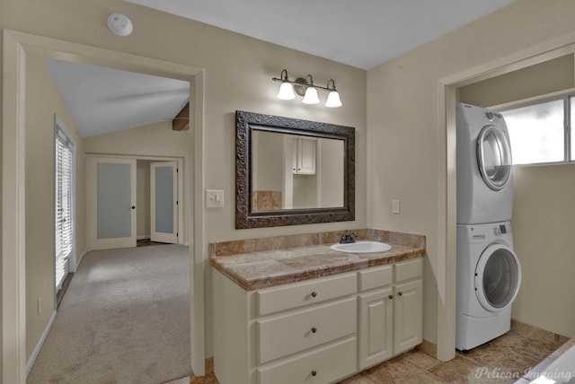 bathroom featuring vaulted ceiling, stacked washer / drying machine, and vanity