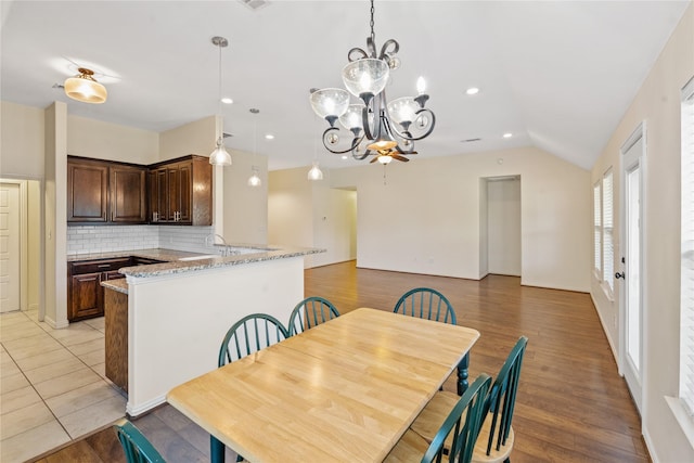 dining room with vaulted ceiling, light hardwood / wood-style floors, and an inviting chandelier