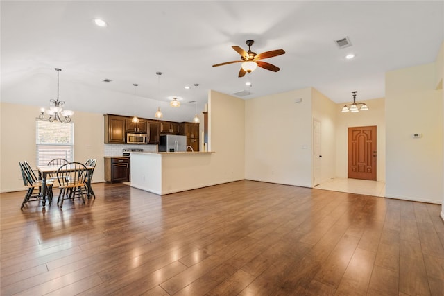 living room with wood-type flooring and ceiling fan with notable chandelier