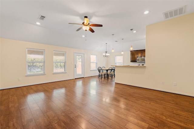 unfurnished living room featuring vaulted ceiling, wood-type flooring, and ceiling fan with notable chandelier