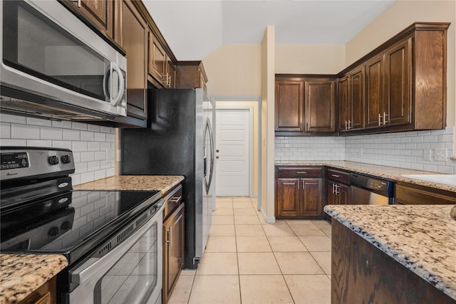 kitchen with light tile patterned floors, backsplash, stainless steel appliances, and light stone counters