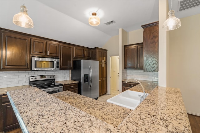 kitchen with sink, hanging light fixtures, stainless steel appliances, kitchen peninsula, and decorative backsplash