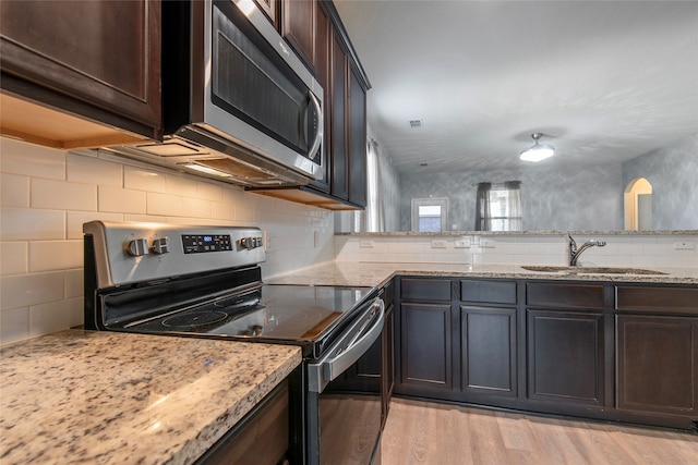 kitchen featuring light stone countertops, appliances with stainless steel finishes, sink, and light hardwood / wood-style flooring