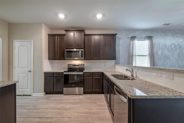 kitchen with stainless steel appliances, light wood-type flooring, dark brown cabinets, sink, and kitchen peninsula