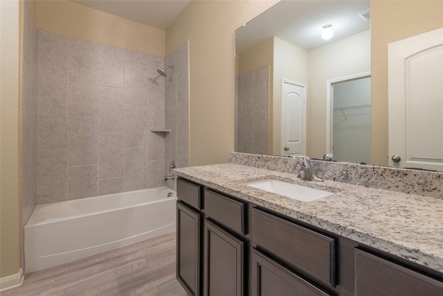 bathroom with wood-type flooring, tiled shower / bath combo, and vanity