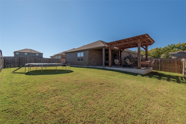 back of house featuring a patio, a lawn, a trampoline, and a pergola