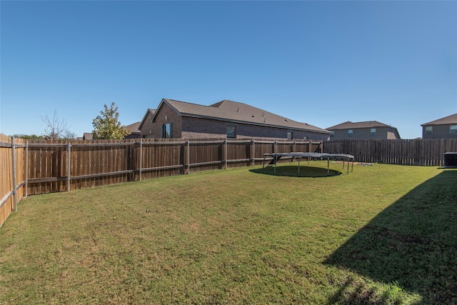 view of yard with central AC and a trampoline