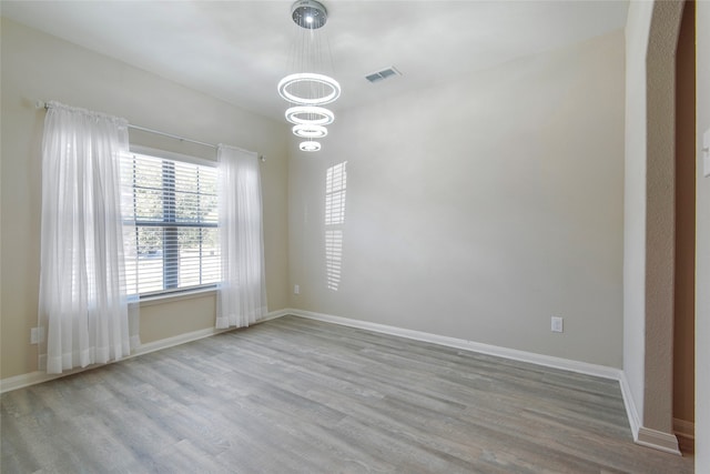 unfurnished room with an inviting chandelier and light hardwood / wood-style flooring