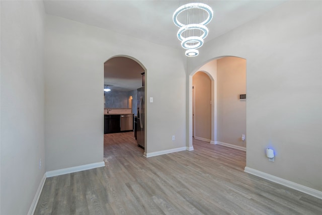 empty room with an inviting chandelier and light wood-type flooring