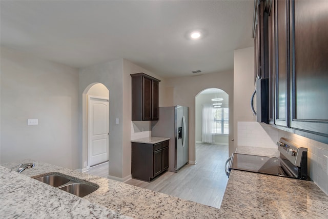 kitchen with light stone counters, sink, light wood-type flooring, and appliances with stainless steel finishes