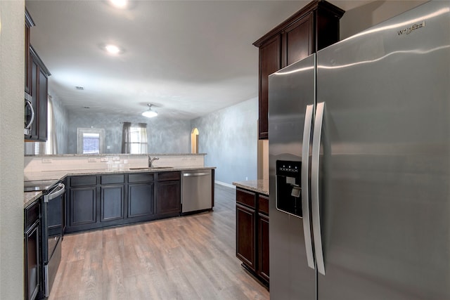 kitchen with kitchen peninsula, sink, light hardwood / wood-style floors, and stainless steel appliances