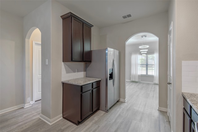 kitchen featuring a notable chandelier, dark brown cabinetry, light stone countertops, stainless steel refrigerator with ice dispenser, and light hardwood / wood-style flooring