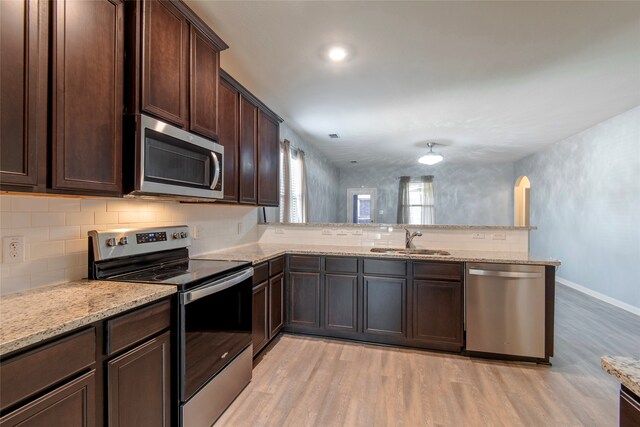 kitchen with kitchen peninsula, sink, light wood-type flooring, and appliances with stainless steel finishes