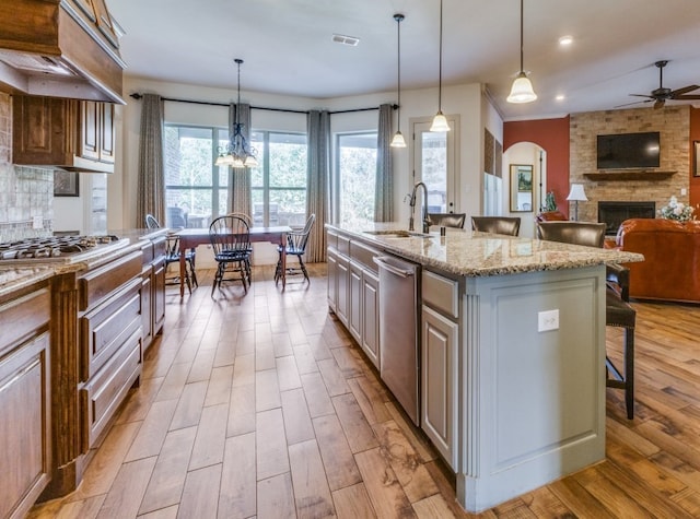 kitchen with light stone countertops, sink, an island with sink, pendant lighting, and a breakfast bar area