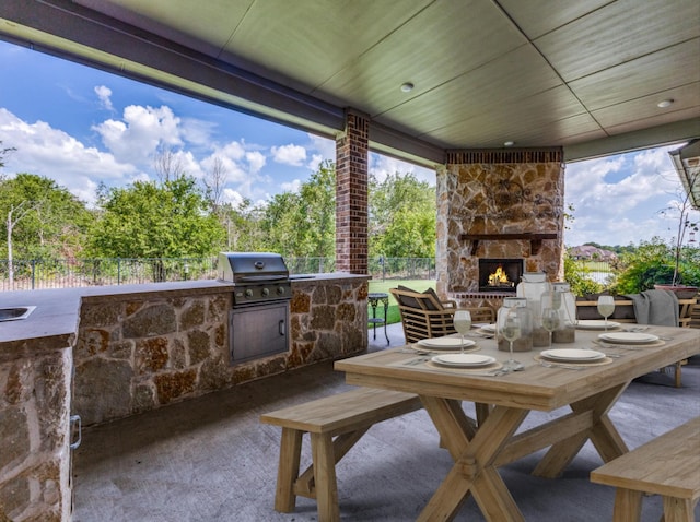 view of patio with area for grilling, an outdoor stone fireplace, and a grill