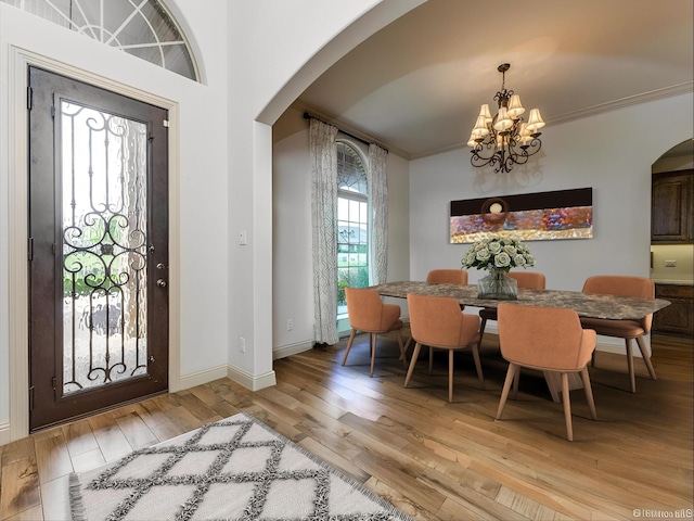 dining area with light hardwood / wood-style floors, crown molding, and a notable chandelier