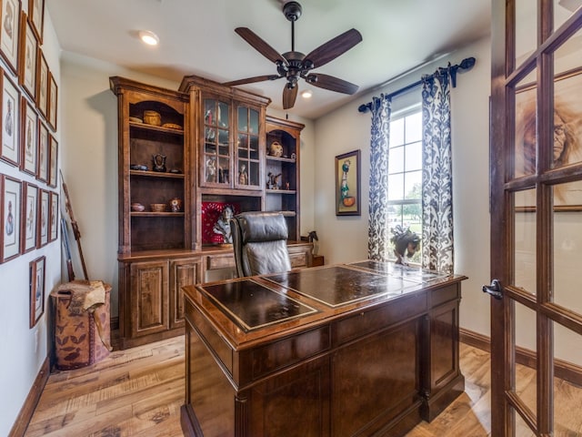 home office with light hardwood / wood-style floors and ceiling fan