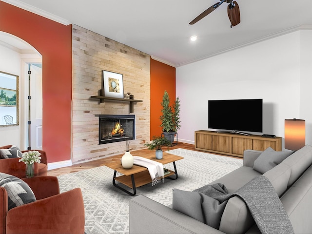 living room featuring a fireplace, ornamental molding, light wood-type flooring, and ceiling fan