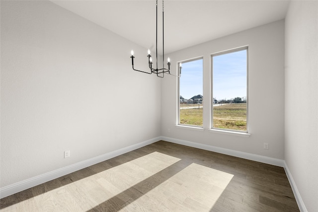 unfurnished dining area featuring baseboards, a chandelier, and dark wood-type flooring