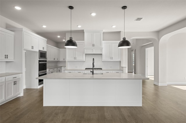 kitchen with decorative backsplash, visible vents, arched walkways, white cabinets, and stainless steel appliances