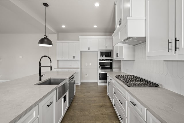 kitchen with light stone countertops, a sink, stainless steel appliances, recessed lighting, and white cabinetry